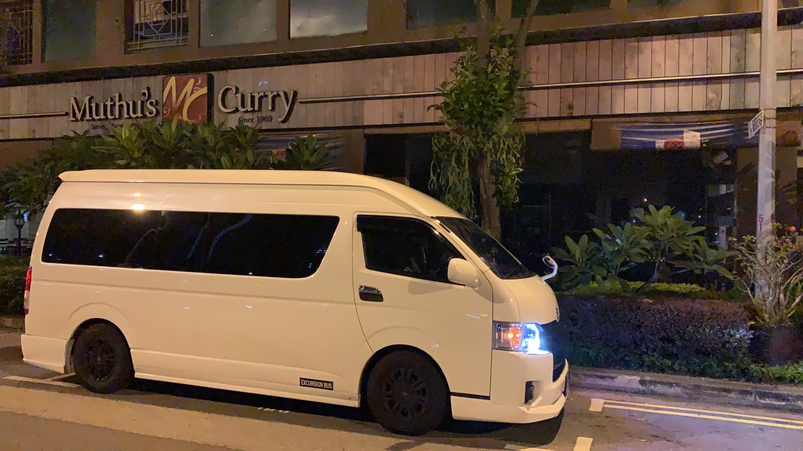 An SKO Limousine maxi cab waiting outside a restaurant in Singapore at night